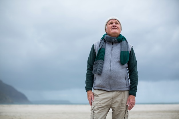 Älterer Mann, der am Strand steht