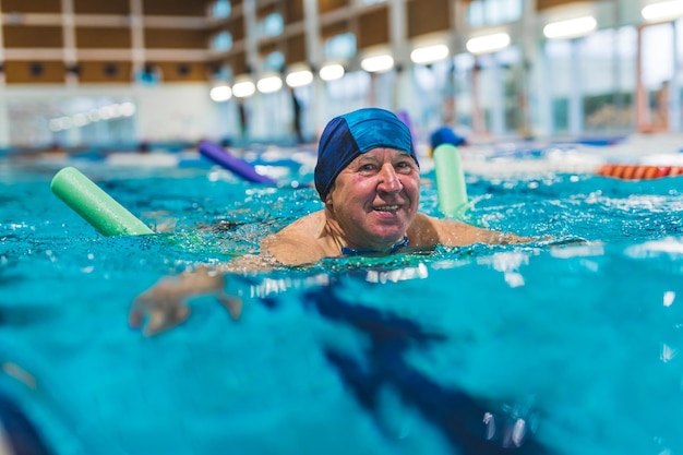 Älterer Mann, der am Swimmingpool schwimmt - aktiver Ruhestand