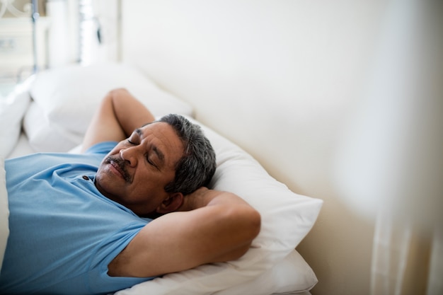 Älterer Mann, der auf Bett im Schlafzimmer schläft