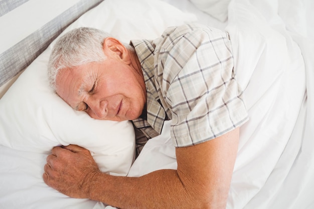 Älterer Mann, der auf Bett im Schlafzimmer schläft