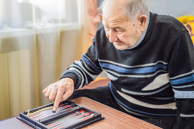 Älterer Mann, der Backgammon in einem Pflegeheim spielt