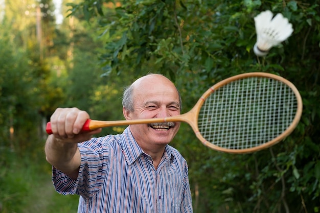 Älterer Mann, der Badminton im Freien auf Picknick spielt