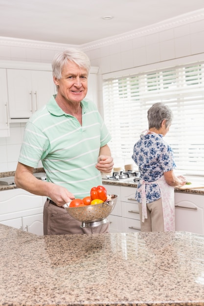 Älterer Mann, der Colander des Gemüses zeigt