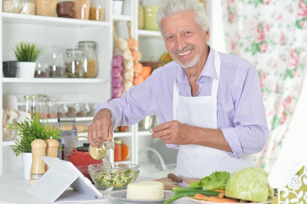 Älterer Mann, der das Abendessen in der Küche zubereitet