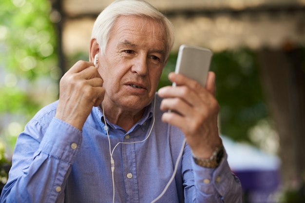 Älterer Mann, der durch Videoanruf im Freien spricht
