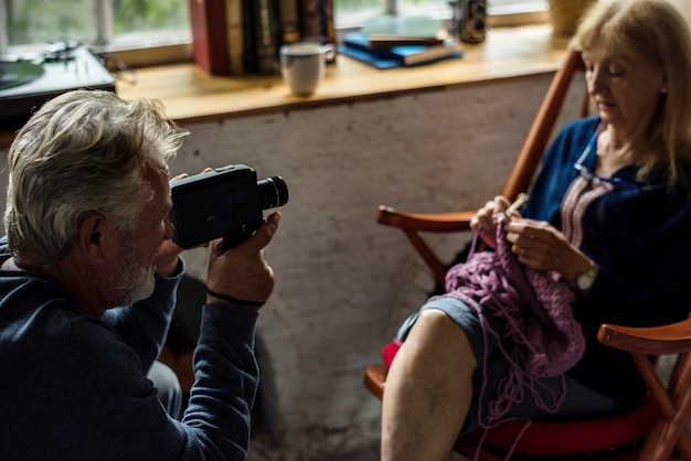 Älterer Mann, der Ehefrau Foto beim Stricken des Handwerkshobby macht