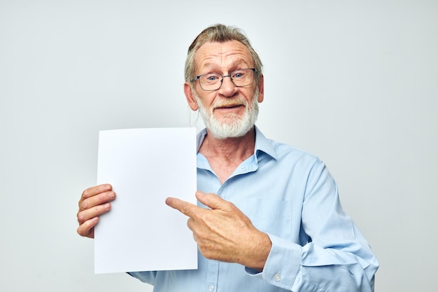 Älterer Mann, der ein Blatt Papier hält, das einen isolierten Hintergrund darstellt