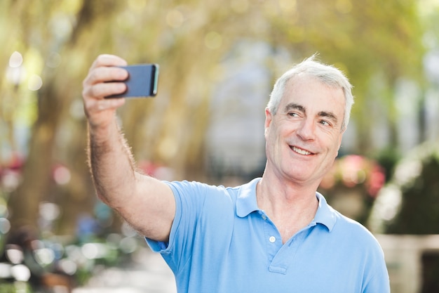 Älterer Mann, der ein Selfie am Park nimmt