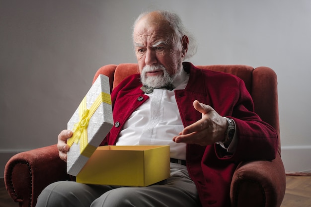 Älterer Mann, der eine Geschenkbox öffnet
