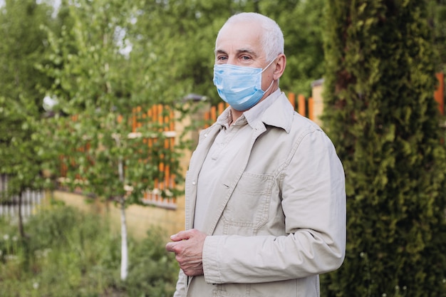 Älterer Mann, der eine Schutzmaske trägt. Natur als Rettung vor dem Virus. Älterer Mann mit Maske im Gesicht.