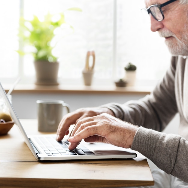 Älterer Mann, der einen Laptop verwendet