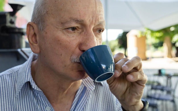 Älterer Mann, der Espressokaffee in einem Café im Freien trinkt