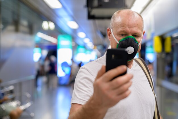 Älterer Mann, der Gesichtsmaske verwendet, um vor Verschmutzungssmog in der Stadt zu schützen