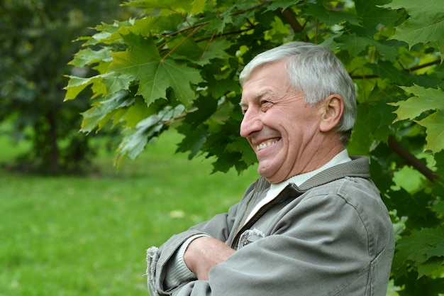 Älterer Mann, der im Herbst im Park spazieren geht