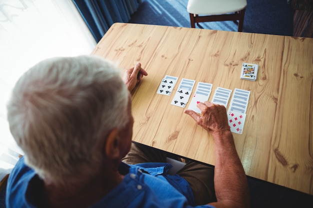 Älterer Mann, der Karten auf einem Tisch spielt