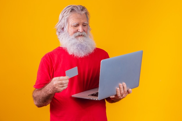 Älterer Mann, der Laptop-Computer und Bankkreditkarte hält. Online-Shopping-Transaktion. Bargeldloses mobiles Banking.