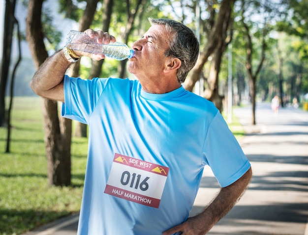 Älterer Mann, der mit Wasser sich erneuert