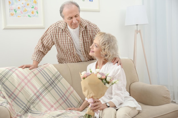 Älterer Mann, der seiner Frau zu Hause Blumen schenkt