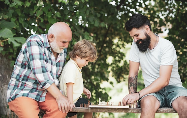 Älterer Mann, der über seinen nächsten Schritt in einem Schachspiel nachdenkt, Familiengeneration, Zukunftstraum und Menschen