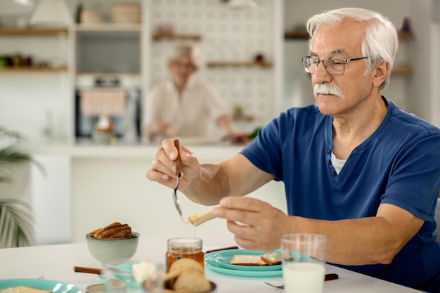 Älterer Mann, der zu Hause ein Frühstück genießt