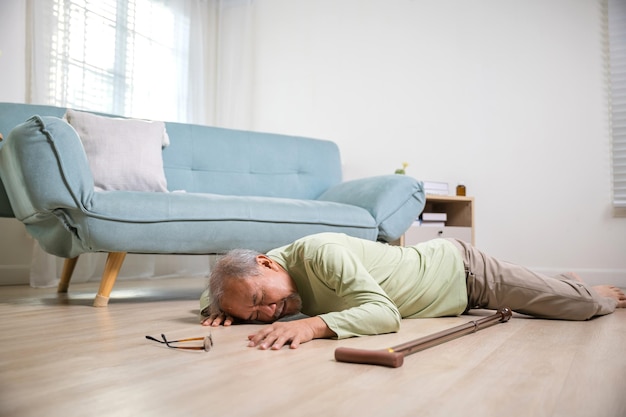 Älterer Mann fällt allein mit Gehstock im Wohnzimmer zu Hause auf den Boden