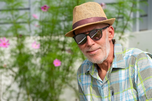 Älterer Mann im Sommerkappen- und -sonnenbrilleporträt
