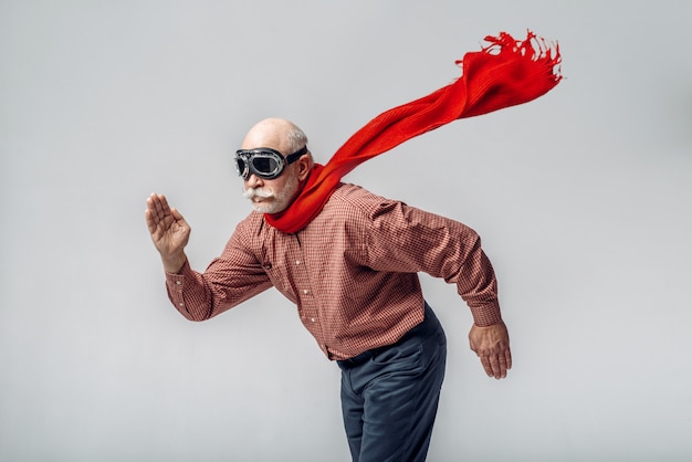 Älterer Mann in einem roten Schal und einer Pilotenbrille