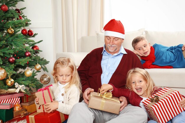 Älterer Mann in Weihnachtsmütze mit Enkelkindern zu Hause