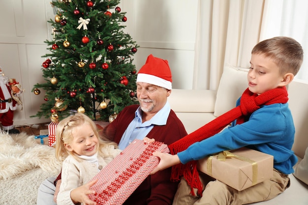 Älterer Mann in Weihnachtsmütze mit Enkelkindern zu Hause