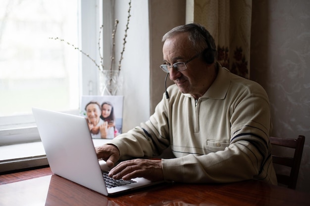 Älterer Mann mit Brille mit Laptop zu Hause.