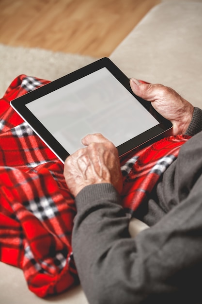 Älterer Mann mit einem Pullover unter Verwendung einer Tablette