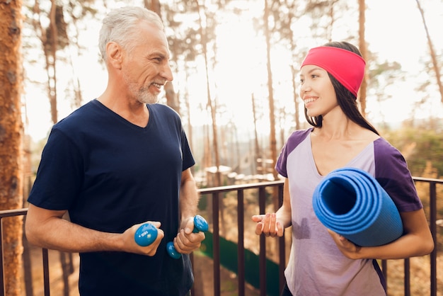 Älterer Mann und Fitnesstrainer sprechen