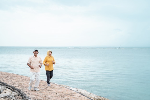 Älterer Mann und Frau, die zusammen am Strand laufen