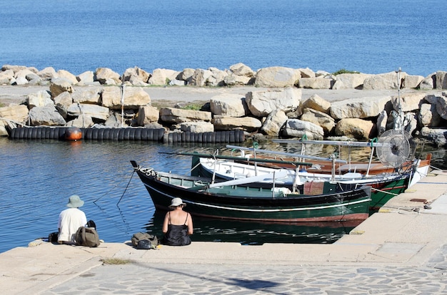 Älterer Mann und Frau sitzen auf den Pierbooten im Hintergrund Porto Cervo Sardinien Italien