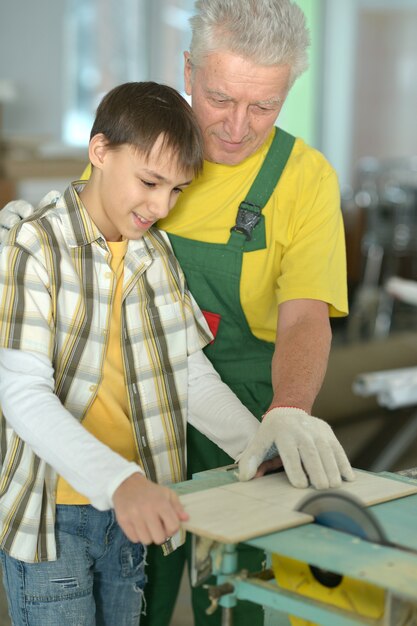 Älterer Mann und sein Enkel reparieren im Zimmer