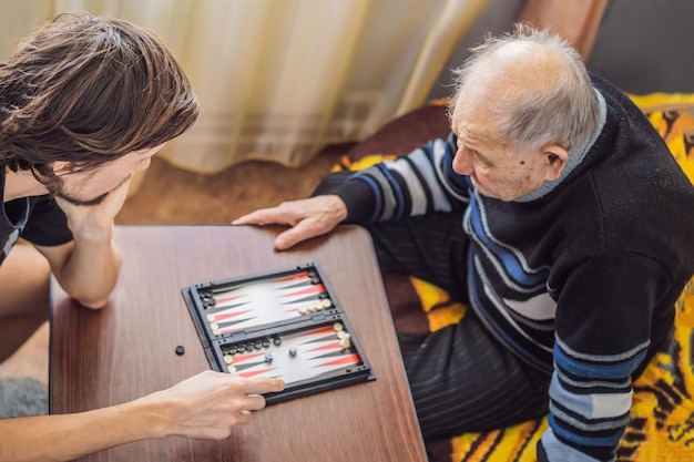 Älterer Mann und sein Enkel spielen Backgammon