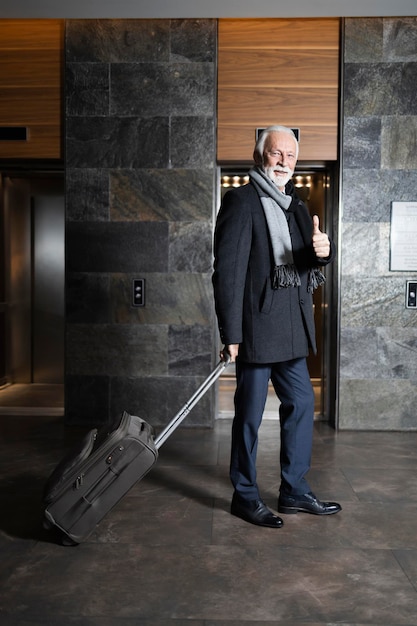 Älterer Mann zeigt Daumen hoch in der Hotellobby