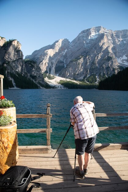 Älterer Mannfotograf, der schönen See in den Dolomitalpen schießt