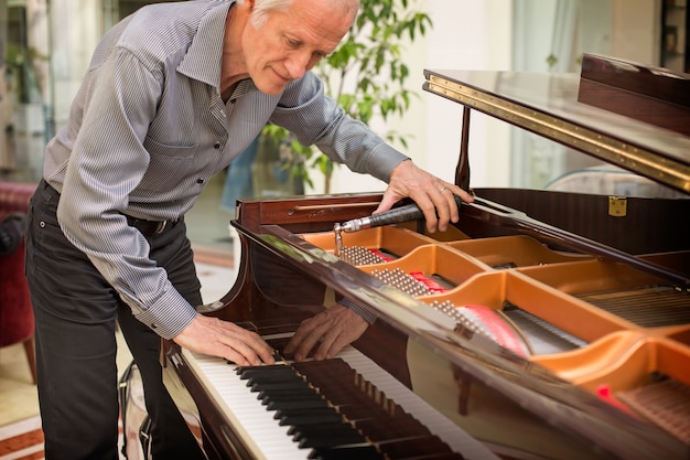 Älterer Musikinstrumententechniker, der eine Klaviertastatur abstimmt.