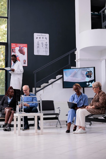 Älterer Patient erklärt dem Assistenten während des Kontrolltermins im Krankenhaus die Krankheitssymptome. Krankenschwester, die medizinisches Fachwissen zu Papieren schreibt, die an der medikamentösen Behandlung arbeiten