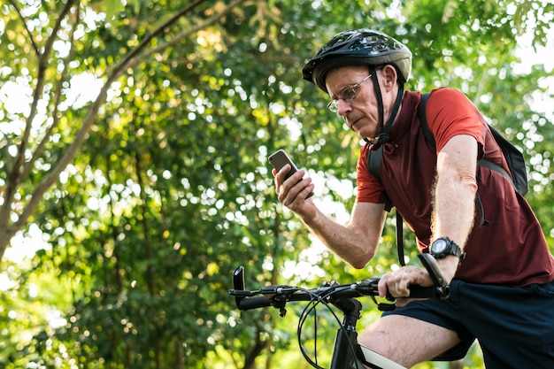 Älterer Radfahrer, der gps am Handy verwendet