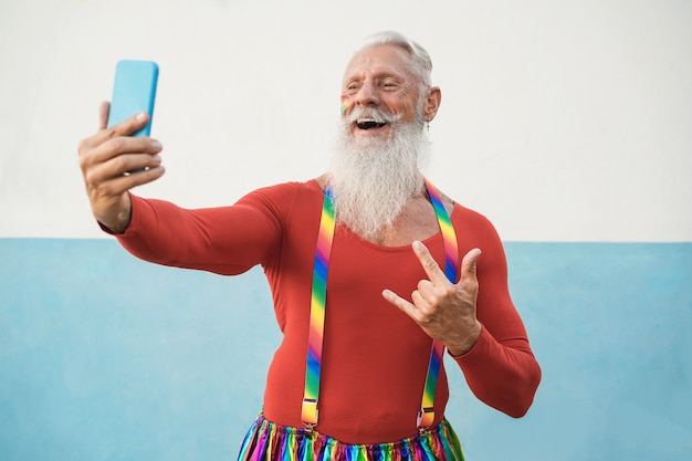 Älterer schwuler Mann, der Handy während lgbt Stolzprotest benutzt - Fokus auf Gesicht