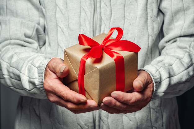 Älterer Senior, der ein Weihnachtsgeschenk hält