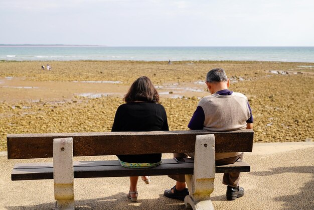 Älteres Ehepaar im Ruhestand, das Meer sucht, sitzt auf einer Bank in Saint Vincent sur Jard in Vendee Beach Frankreich