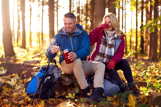 Älteres Ehepaar im Ruhestand für Ruhe und heißes Getränk auf Spaziergang durch die Herbst- oder Winterlandschaft