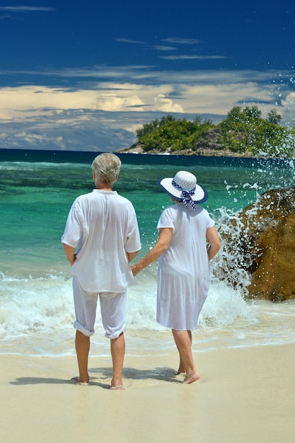 Älteres Ehepaar steht am Strand mit Blick aufs Meer