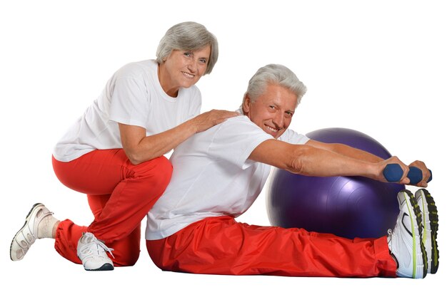 Älteres Ehepaar trainiert, sitzt auf dem Boden eines Fitnessstudios isoliert auf weiß