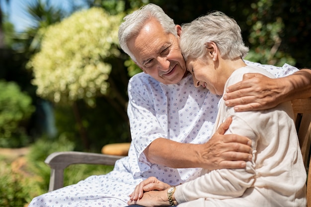 Älteres Paar, das am Krankenhausgarten umarmt