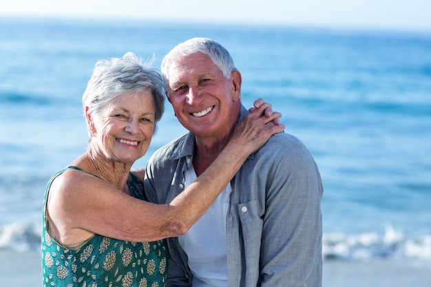 Älteres Paar, das am Strand umarmt