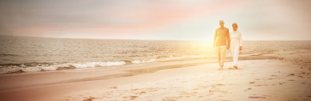 Älteres Paar, das an einem sonnigen Tag am Strand spazieren geht